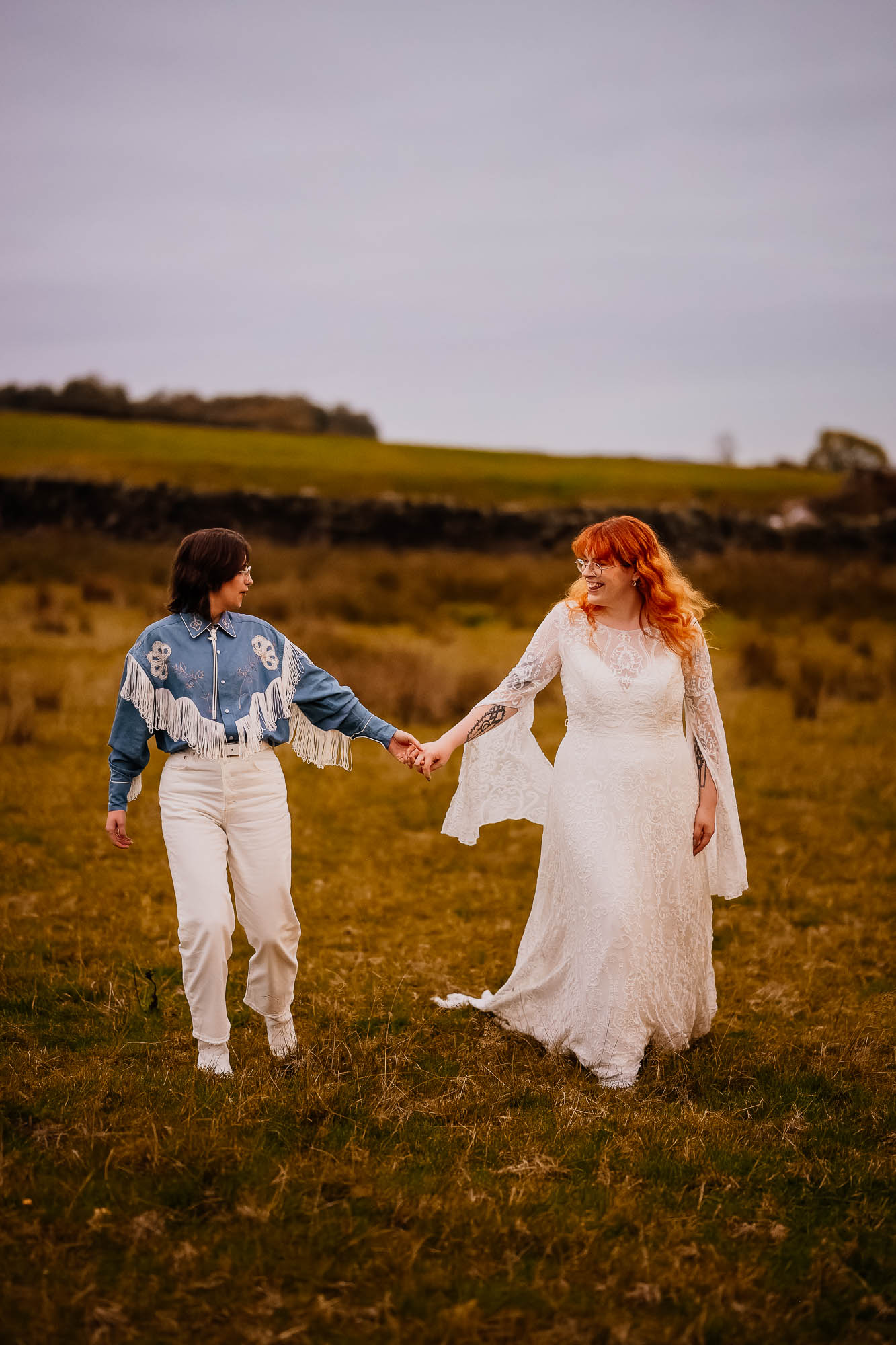 Couple walking holding hands through a field