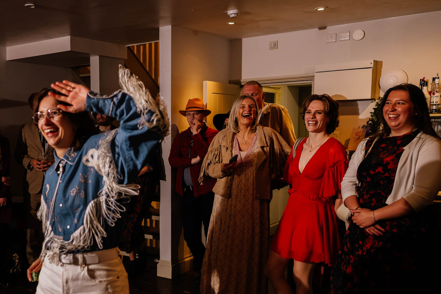 Guests laughing in the background whilst couple dances