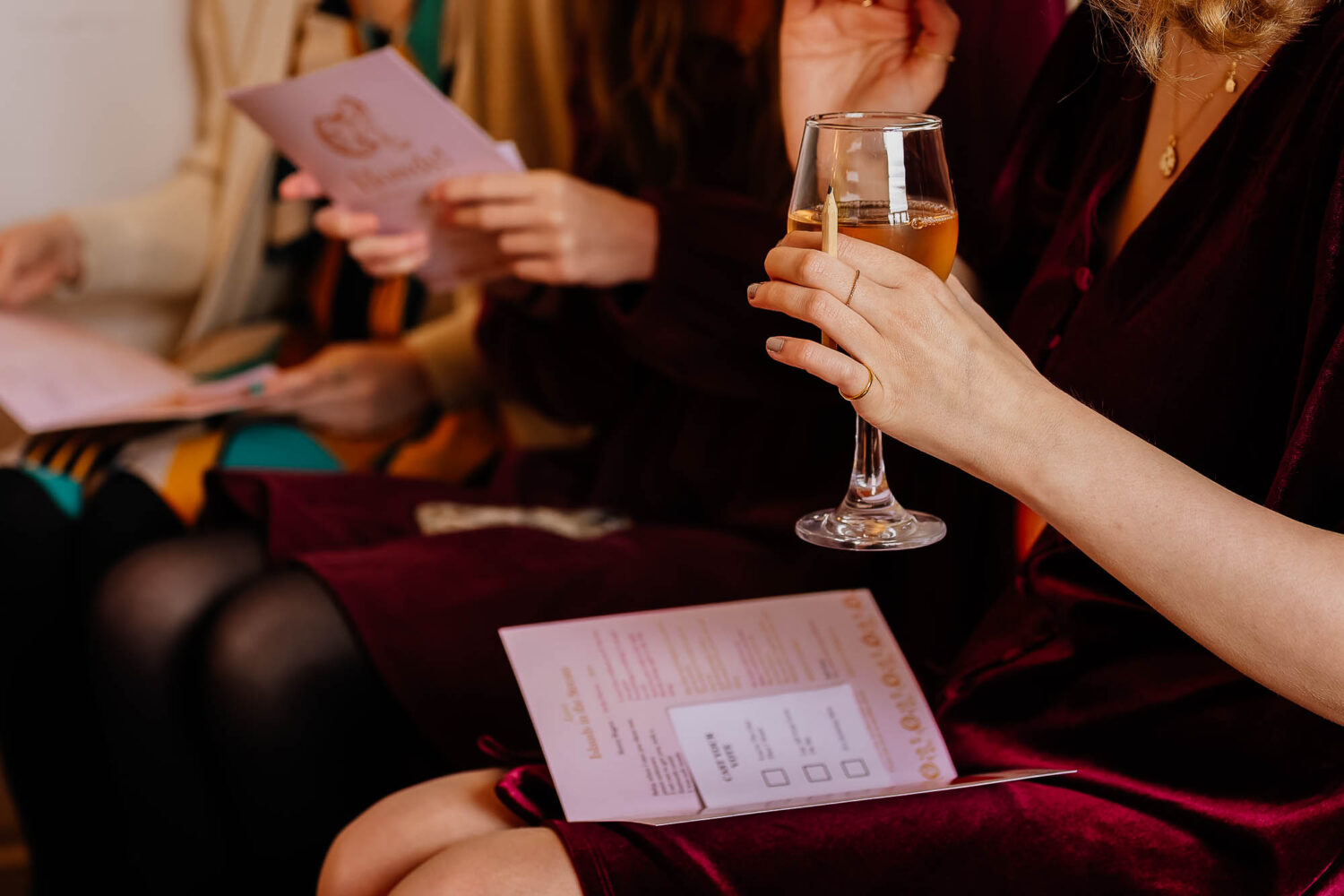 Guest sat in ceremony holding a glass of wine
