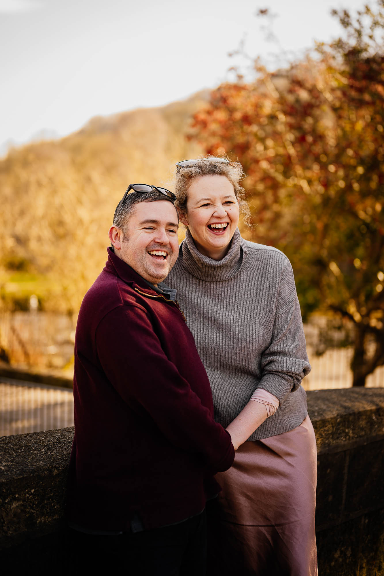 Couple laughing holding hands with autumnal background