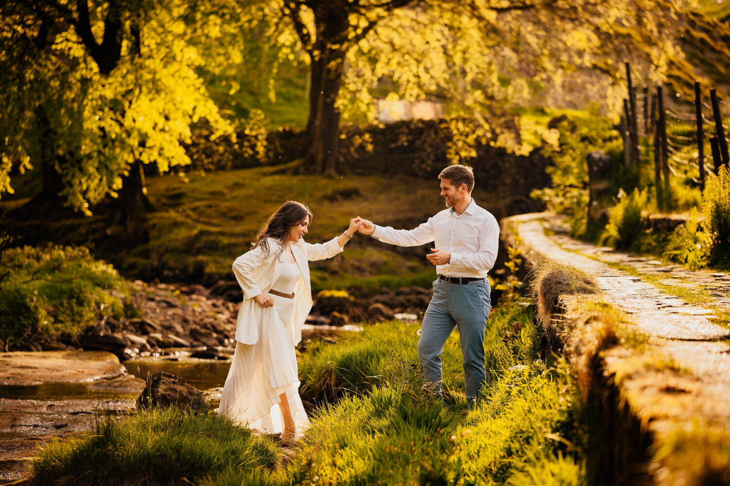 Couple holding hands by a stream in sunlight