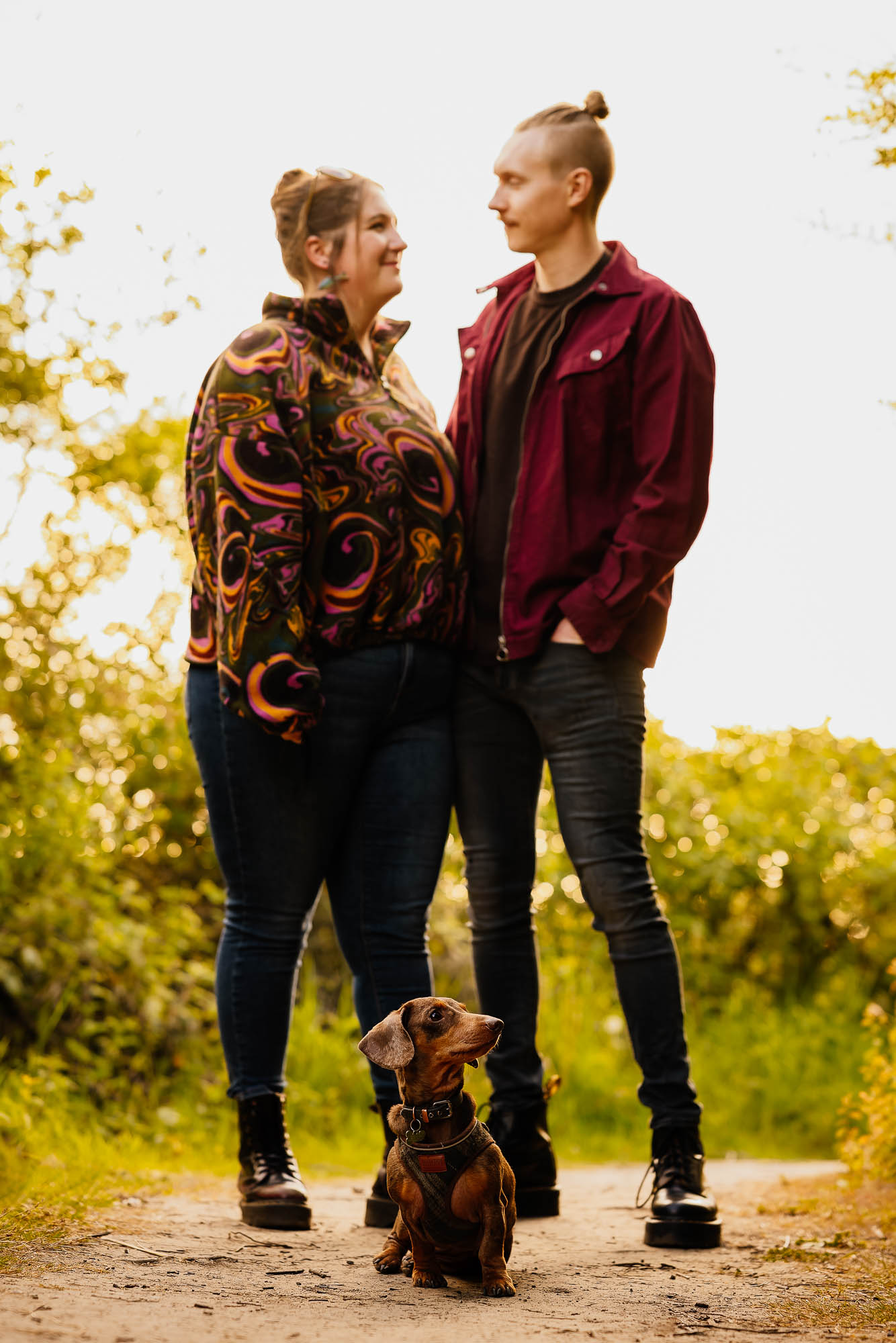 Sausage dog with couple behind on their pre-wedding shoot