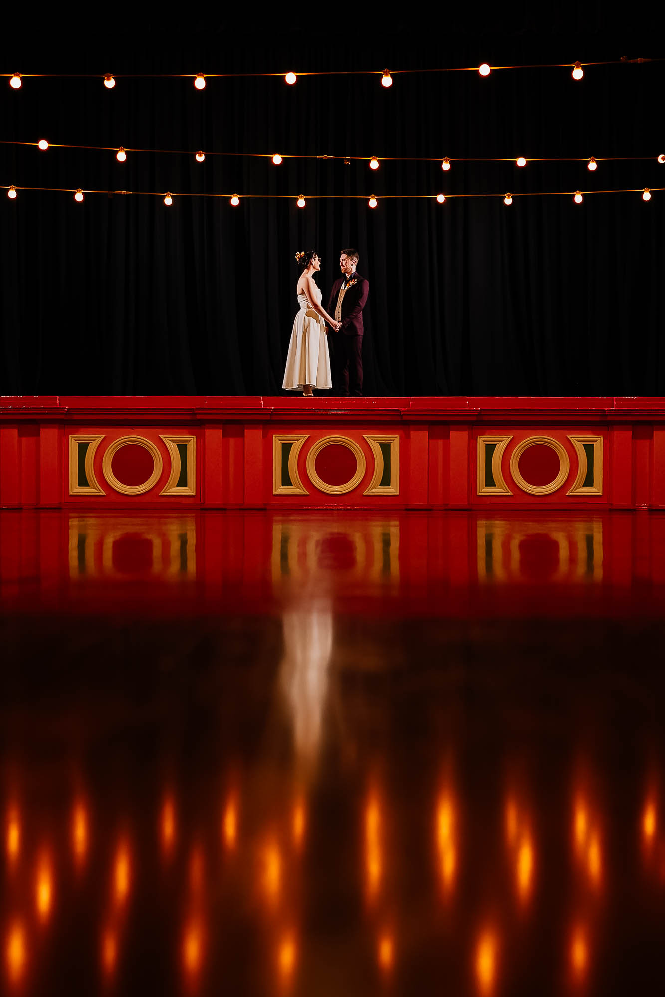 Couple on the stage at Victoria Hall with fairy lights