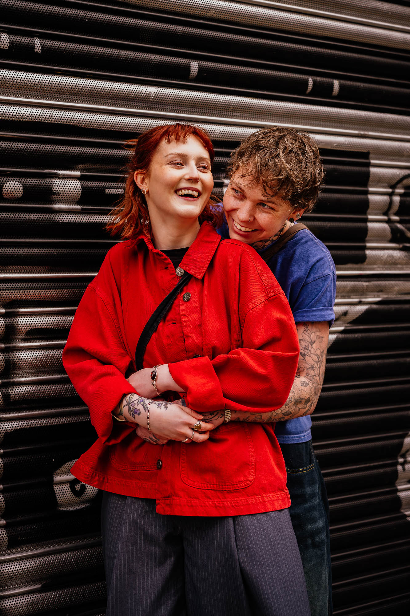 Couple hugging in front of metal shutters