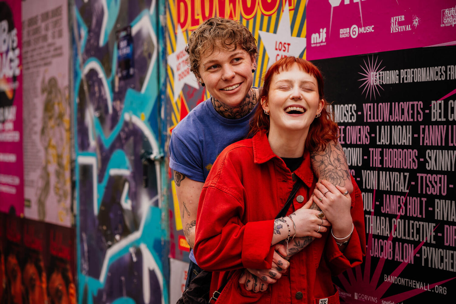 Couple laughing and hugging in front of Thomas Street posters