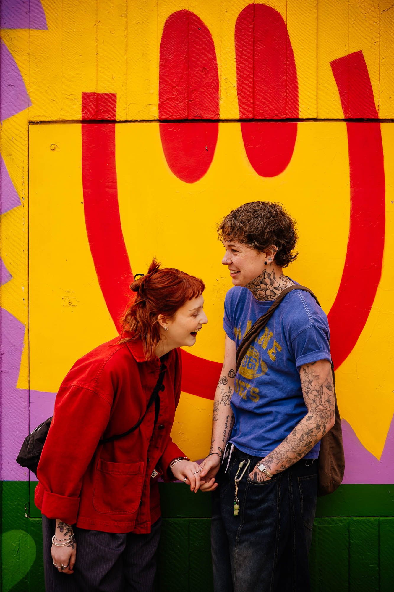 Couple laughing under smiling mural in Stevenson Square