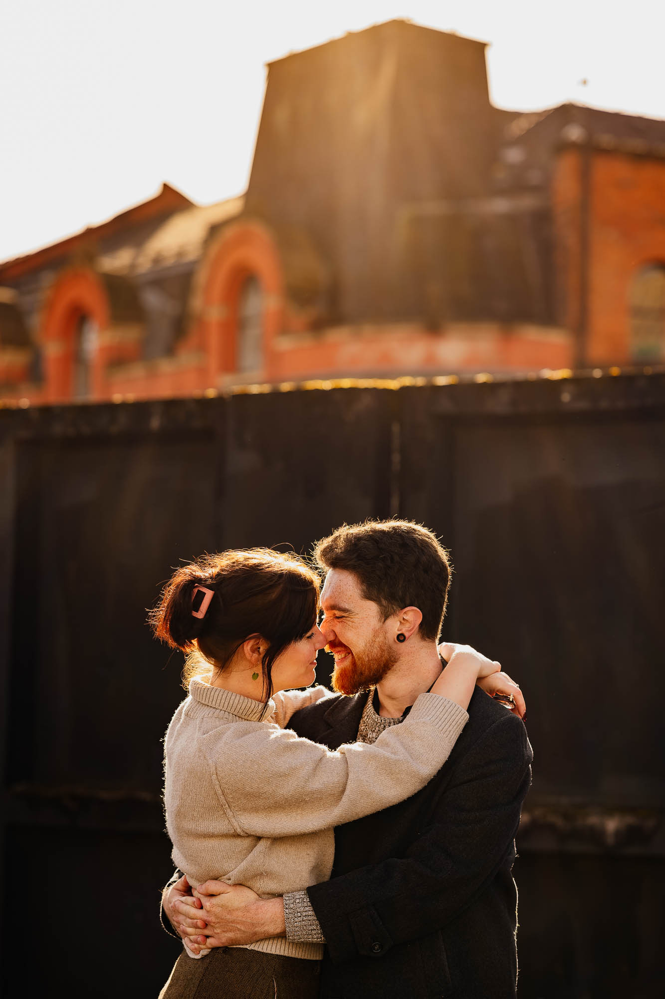 Couple hugging on car park roof with sun flare shining on them