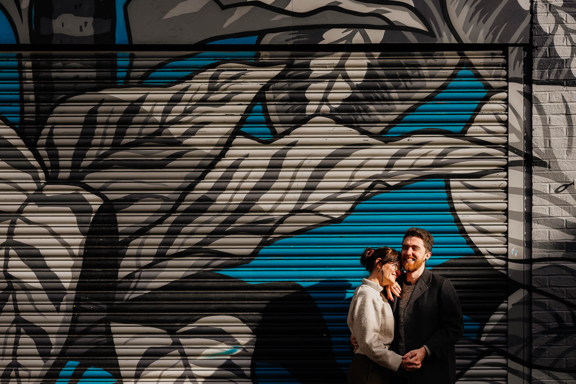 Couple in sun in front of Cane and Grain shutters on Thomas Street