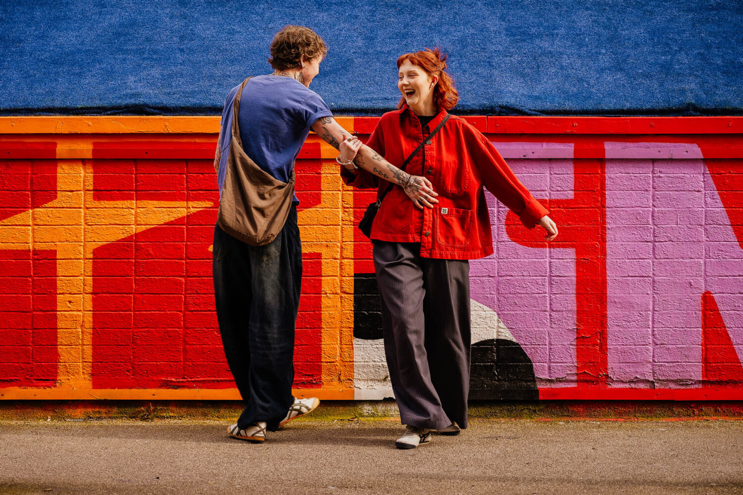 Couple spinning around in front of colourful Northern Quarter backdrop