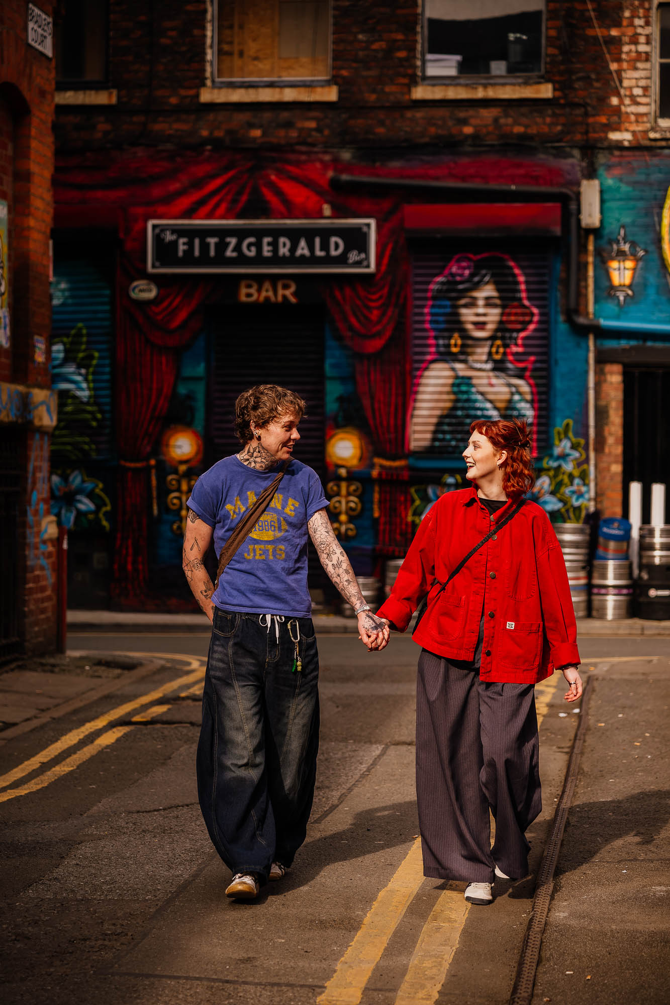 Couple hand in hand walking in front of Fitzgerald Bar in the Northern Quarter