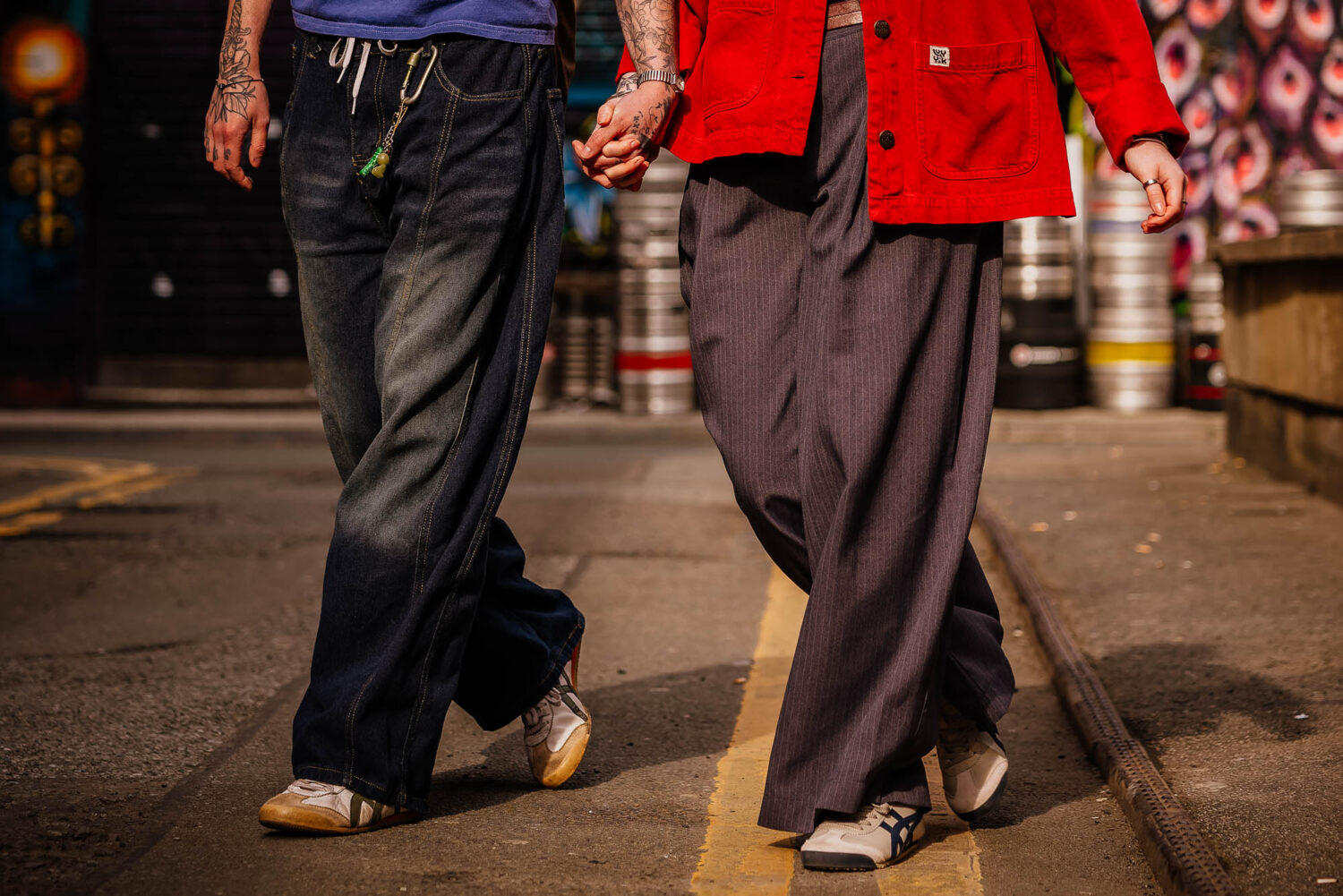 Couple in matching step holding hands walking through urban Manchester