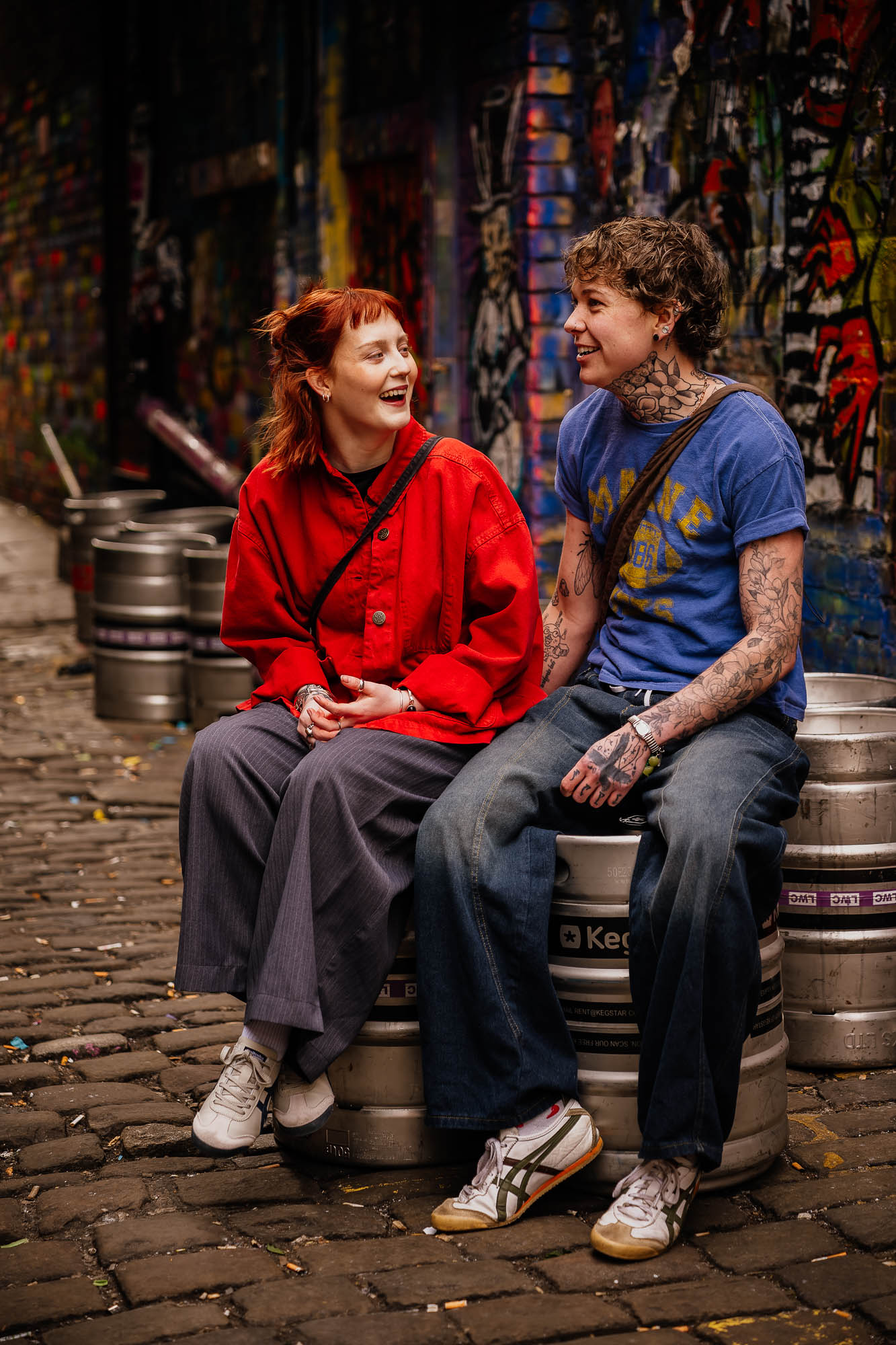 Couple sat laughing on beer kegs in the Northern Quarter