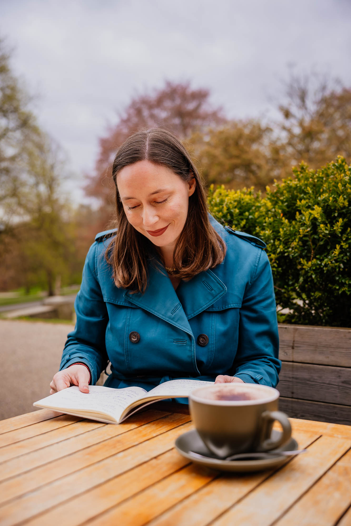 Woman sitting outside with notebook and hot drink