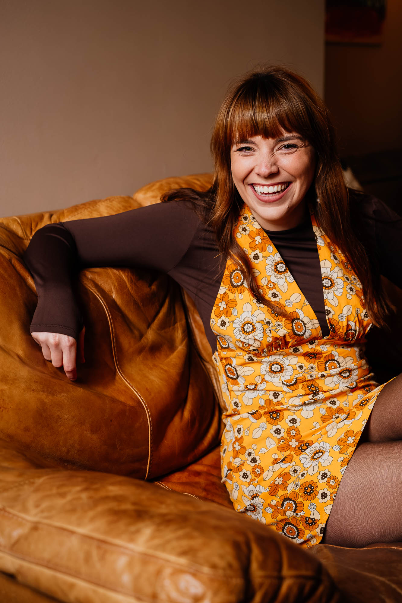 Portrait of woman in yellow retro dress on tan leather sofa