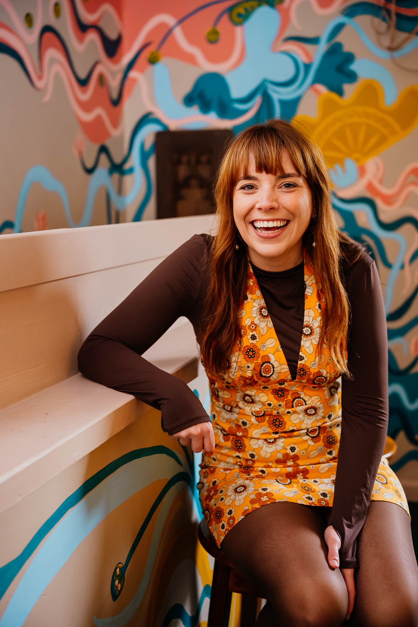 Portrait of woman in yellow retro dress laughing with colourful backdrop