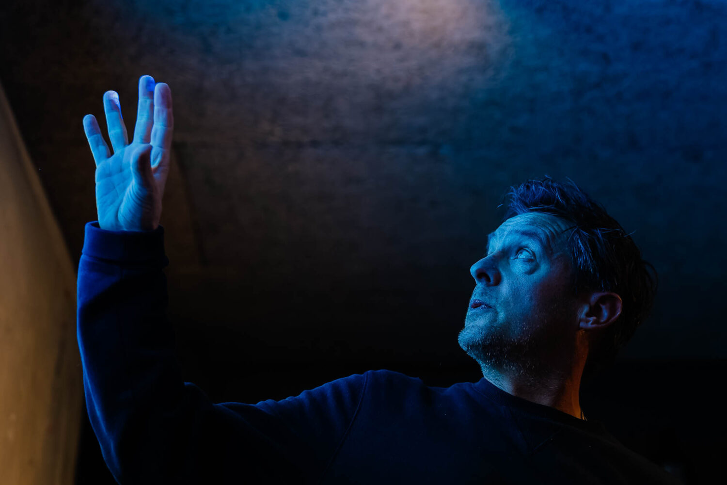 Man holding hands up with blue light on his face