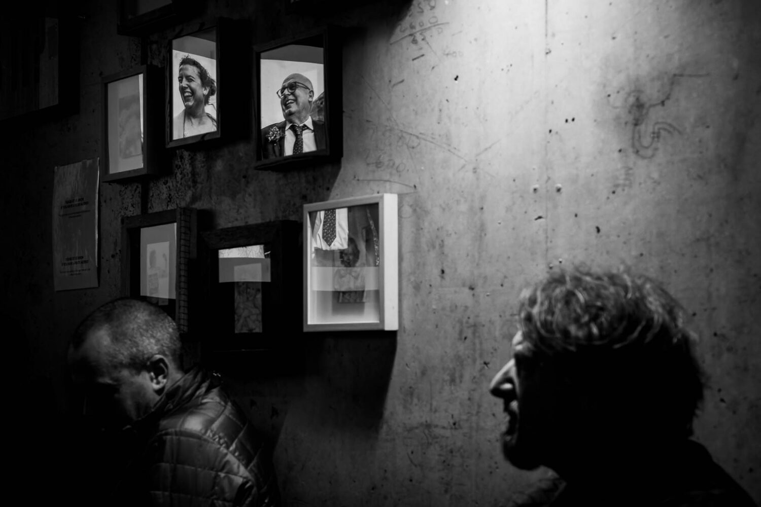 Reflection of man and woman in picture frames on wall with silhouette in front