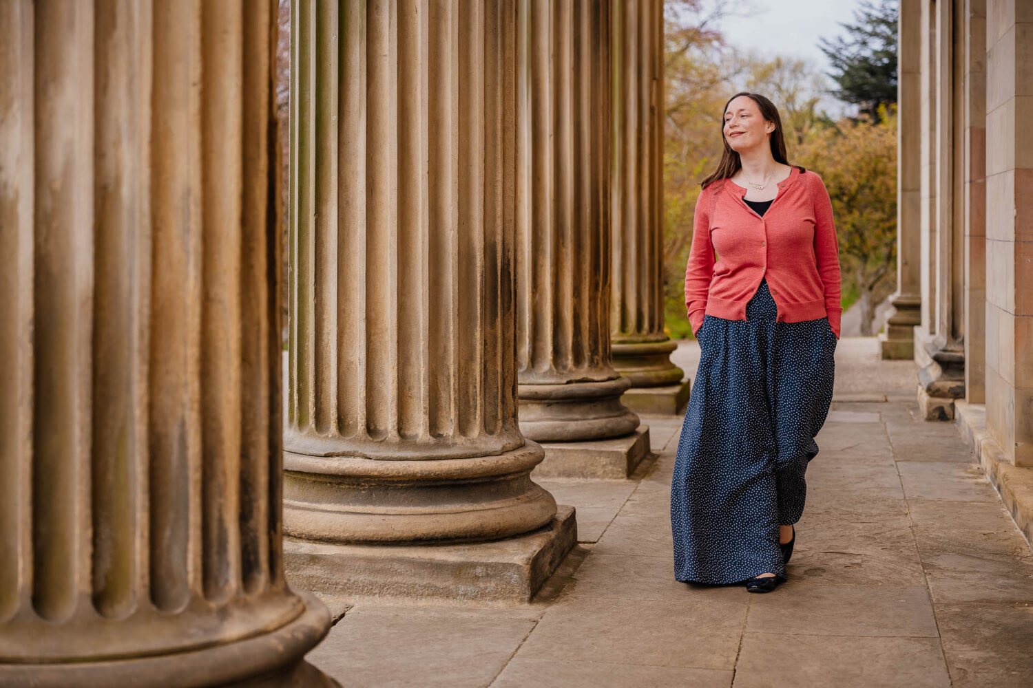 Woman walking through mansion building with hands in pockets