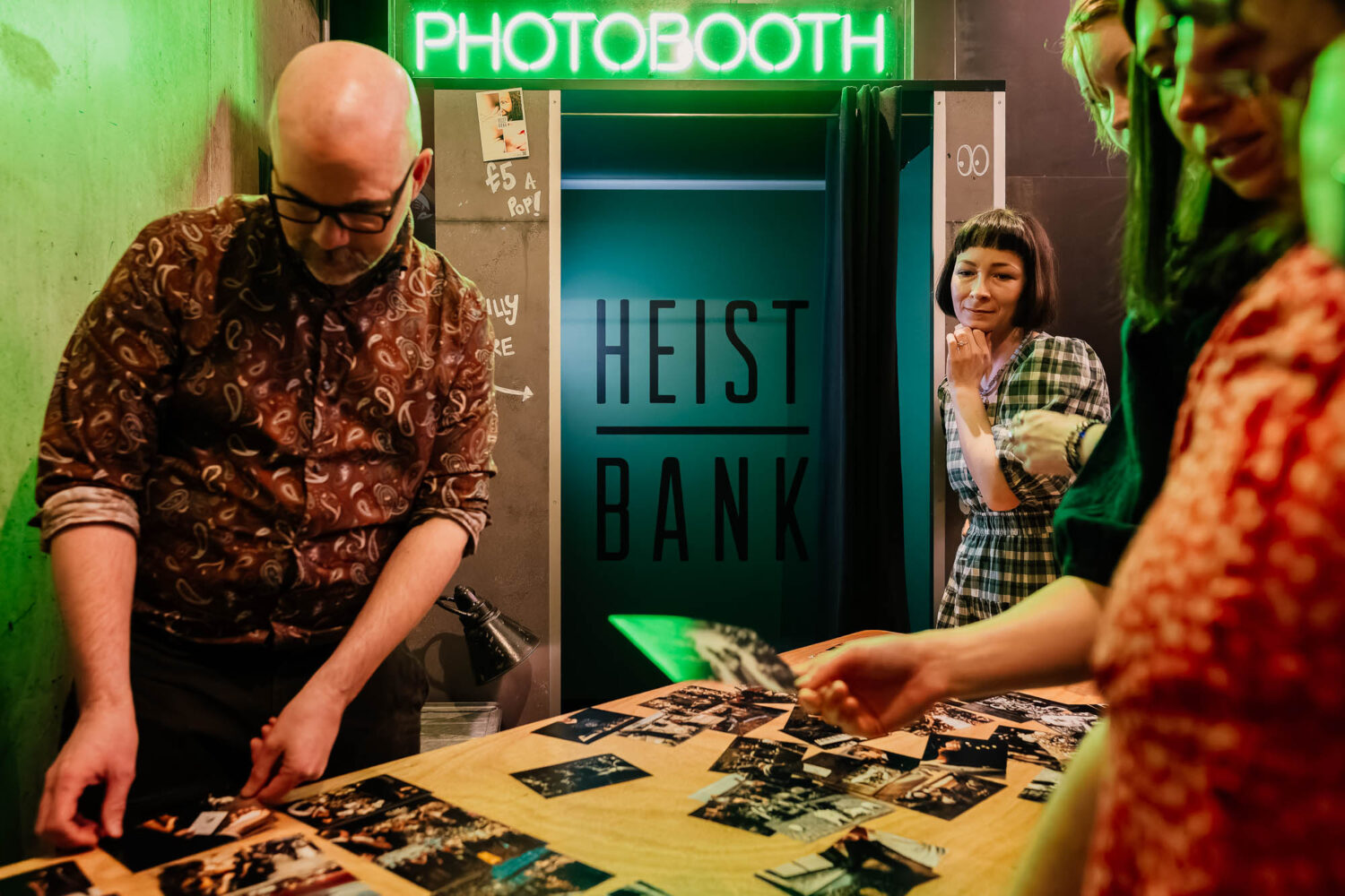 People organising photos on a table with a photobooth in the background