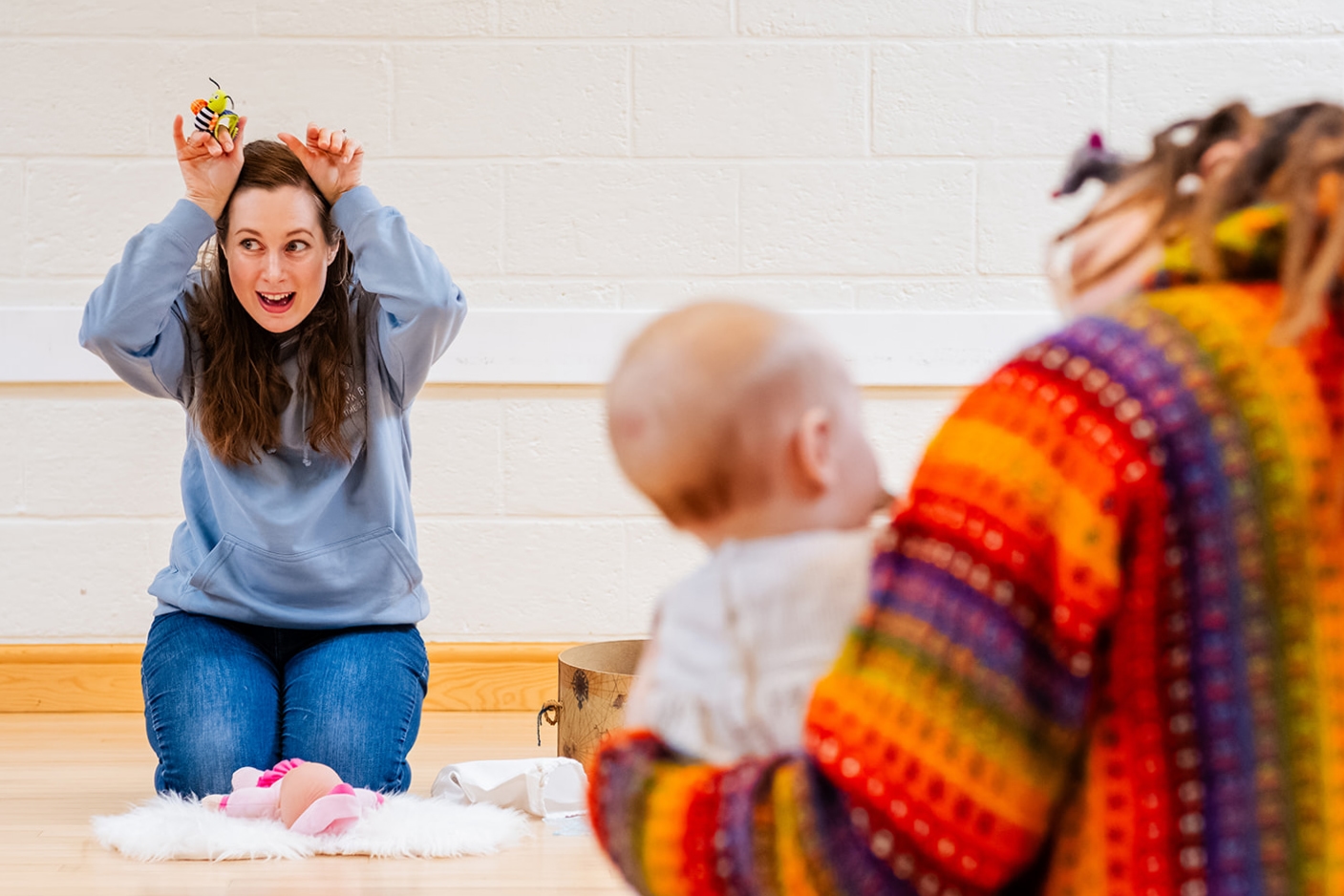 woman gesturing with toys during baby class