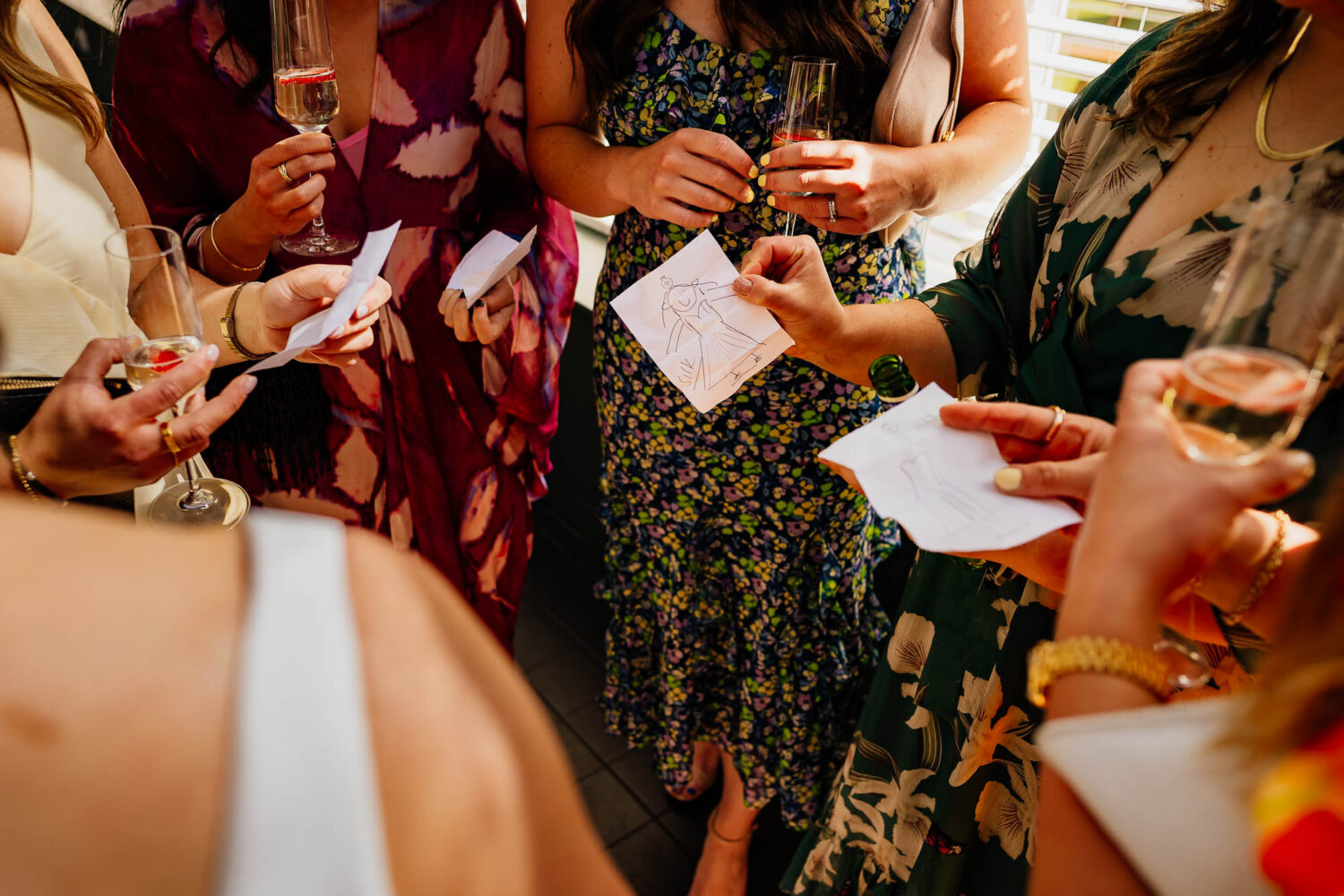 Guests sharing drawings of wedding dress guesses with bride