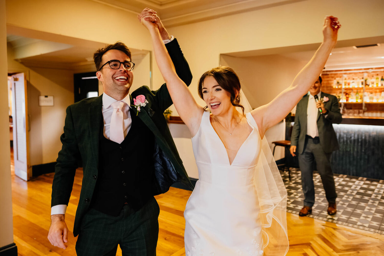 Bride and groom raise arms and enter the main room at The Faversham