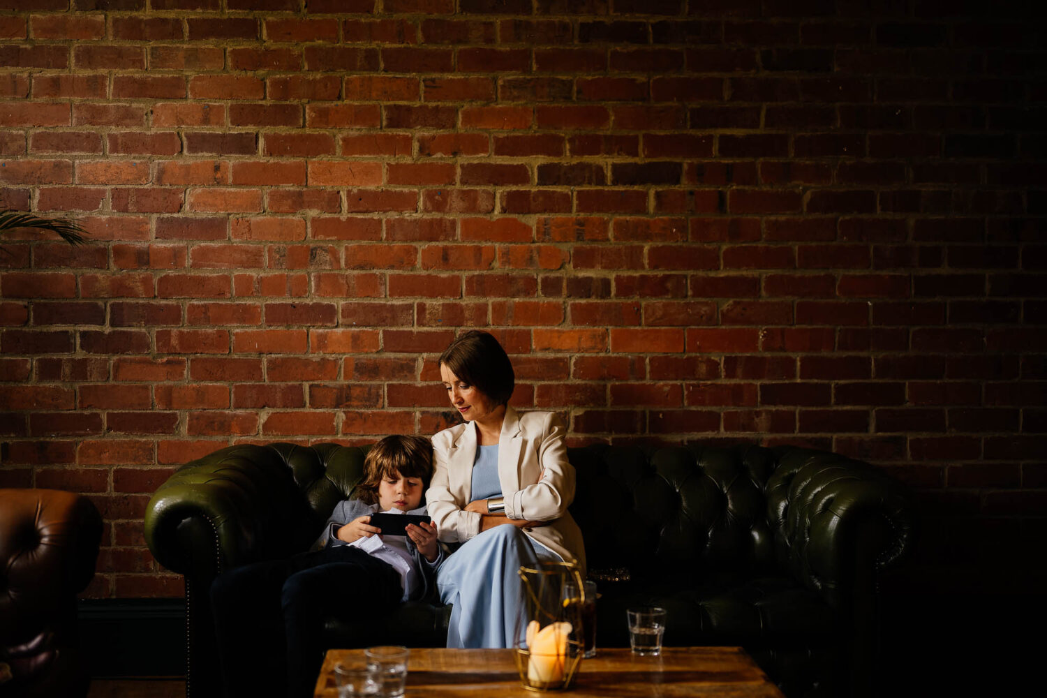 Mother and son sat on sofa under exposed brick wall