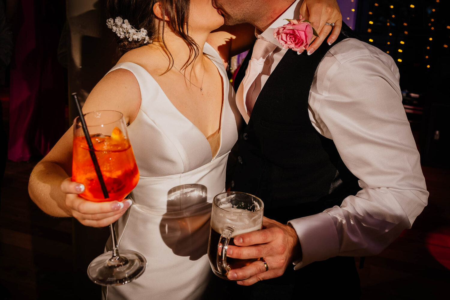 Couple holding drinks and kissing at The Faversham wedding