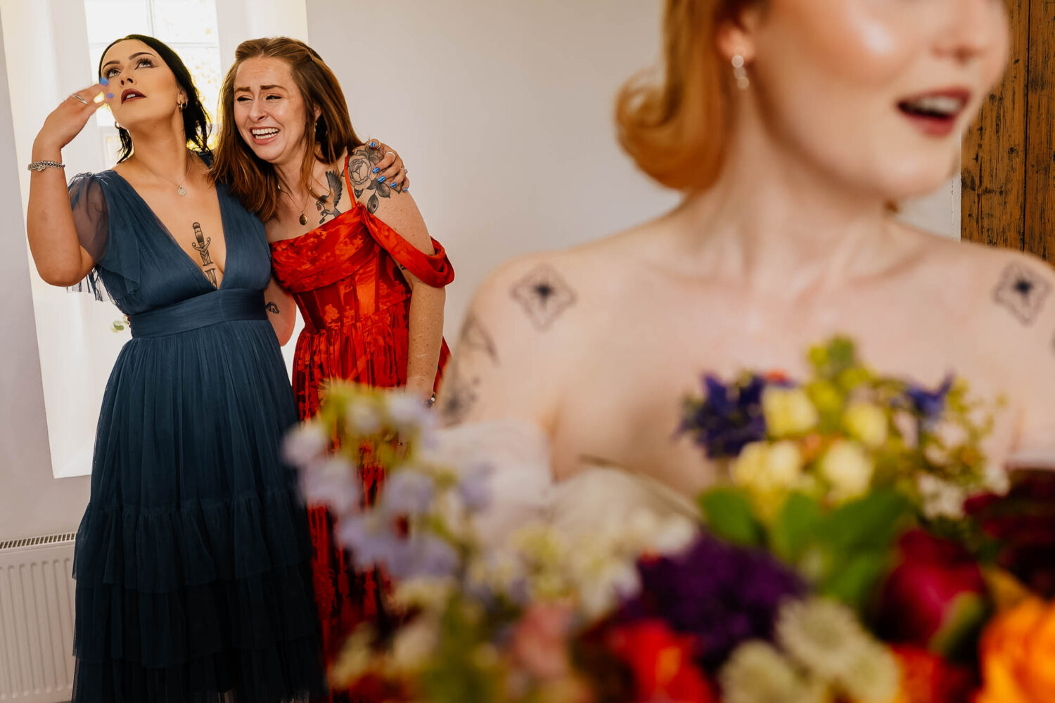 Bridesmaids share emotional hug behind the bride