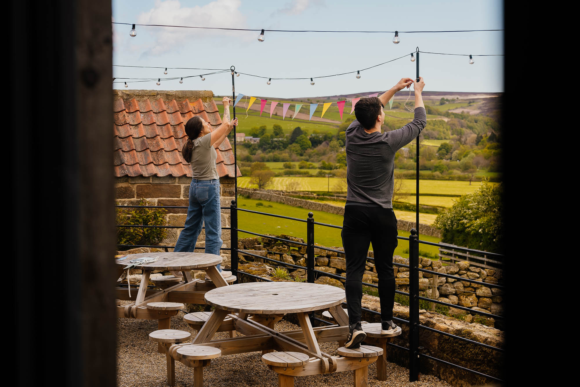Two people putting up bunting on fence outside Danby Castle