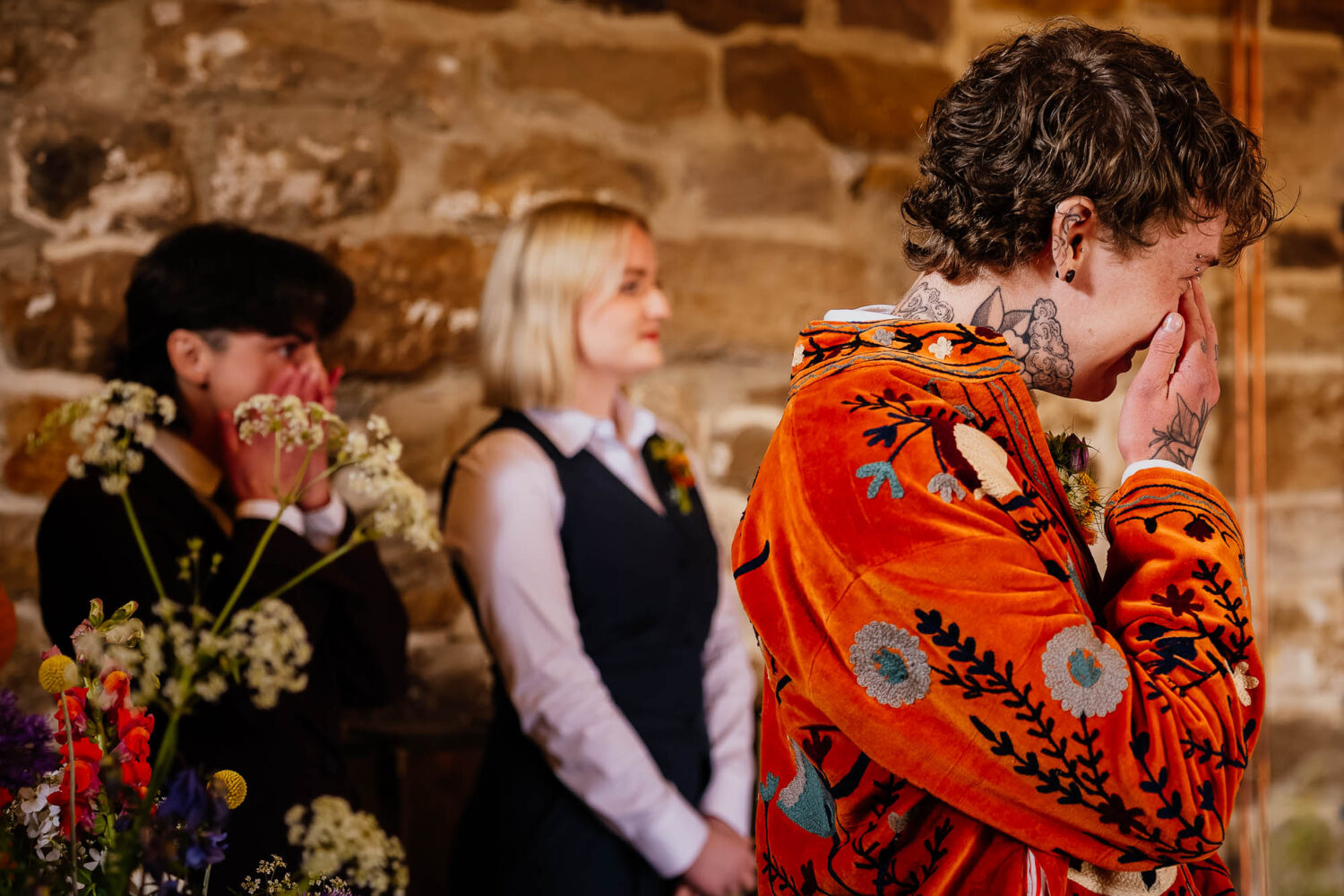 Groom wiping a tear away with friends stood behind