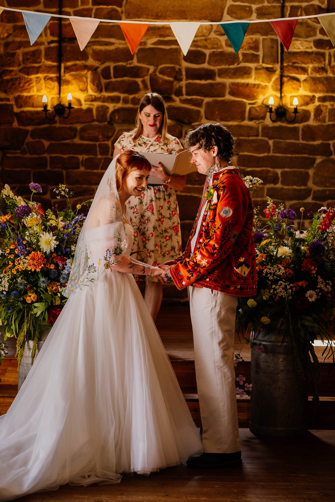 Couple holding hands standing between flowers and bunting