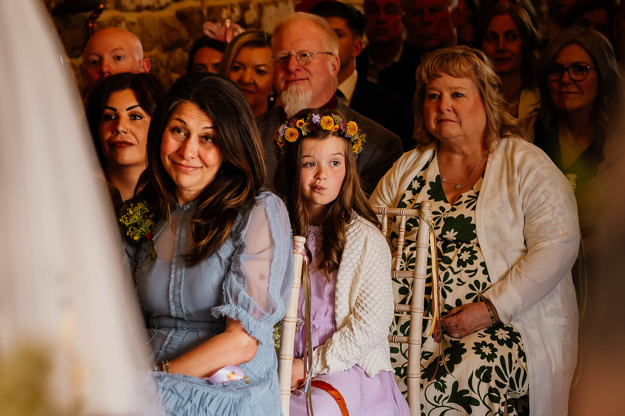 Flower girl pulling a face looking bored during wedding ceremony