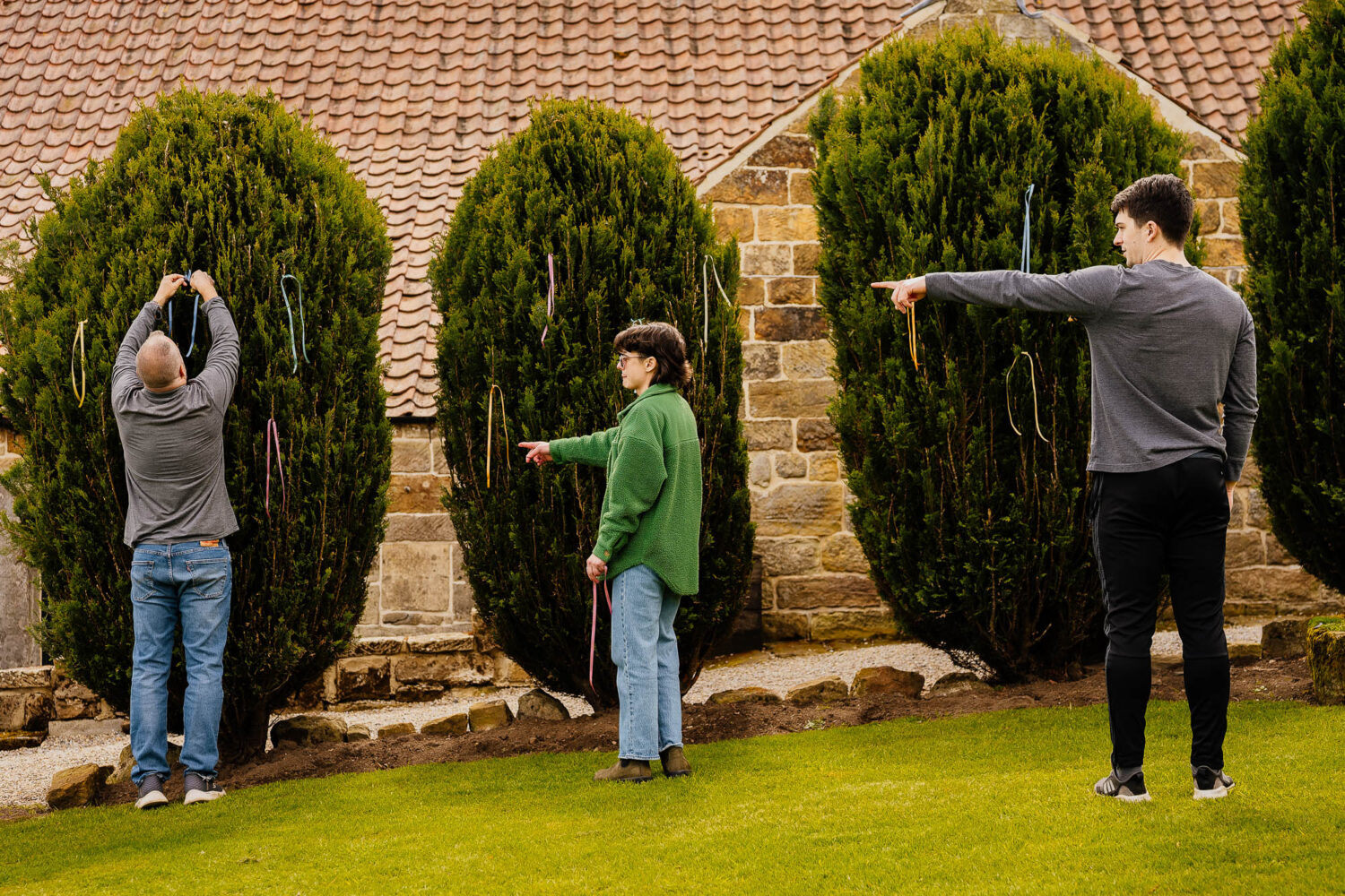 Three people arranging ribbons on bushes