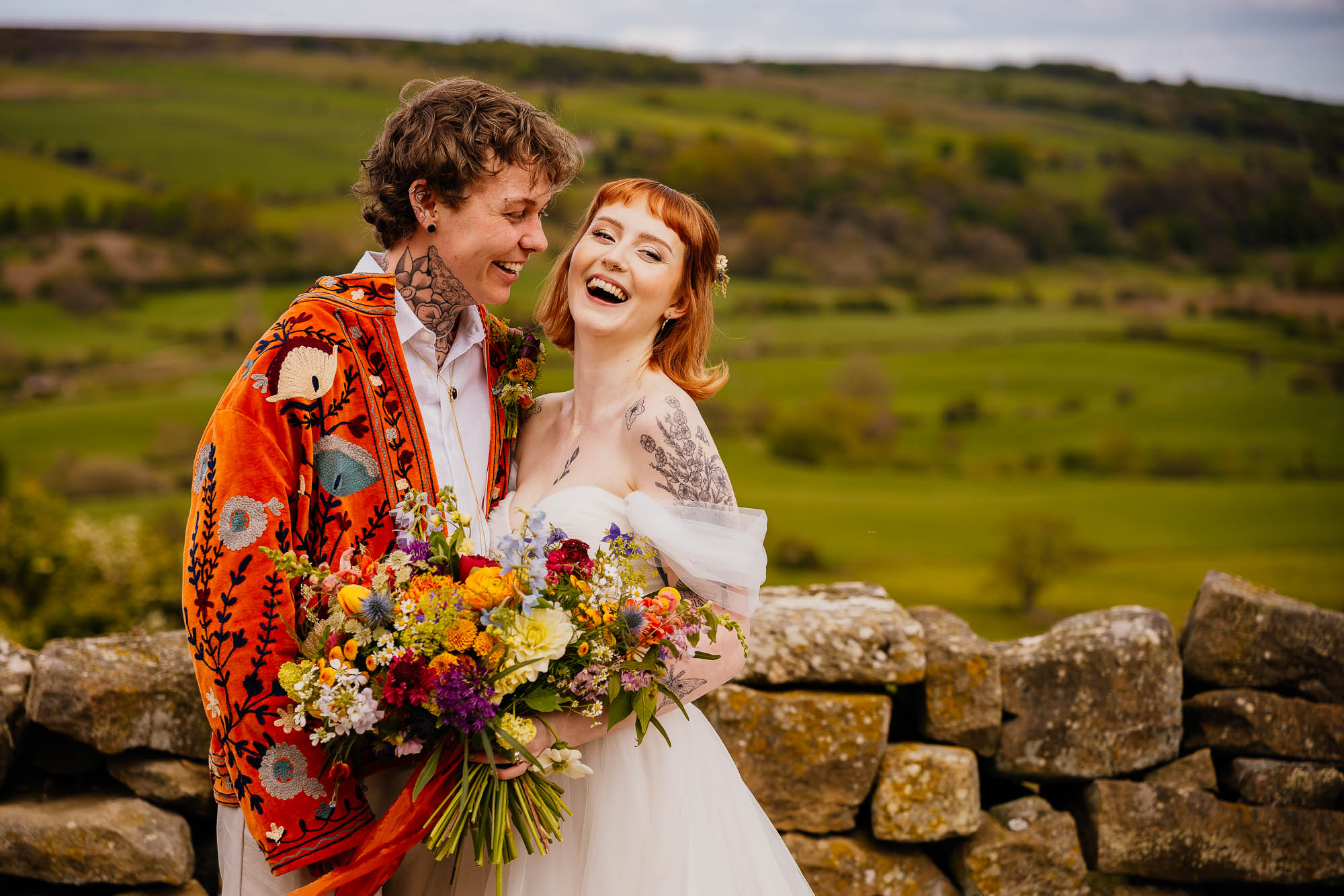 Smiling ouple portrait against dry stone wall and moors backdrop at Danby Castle wedding