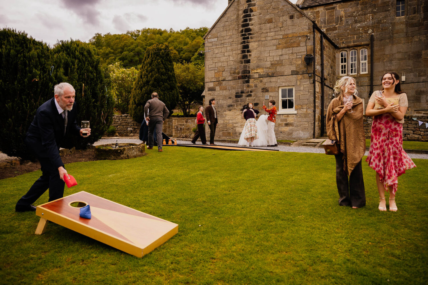 Bride hugging guest with cornhole being played in the foreground