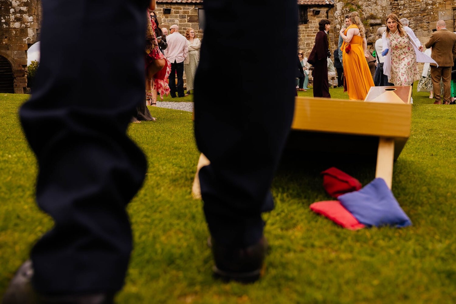 Woman throwing beanbags for cornhole with mans legs in foreground