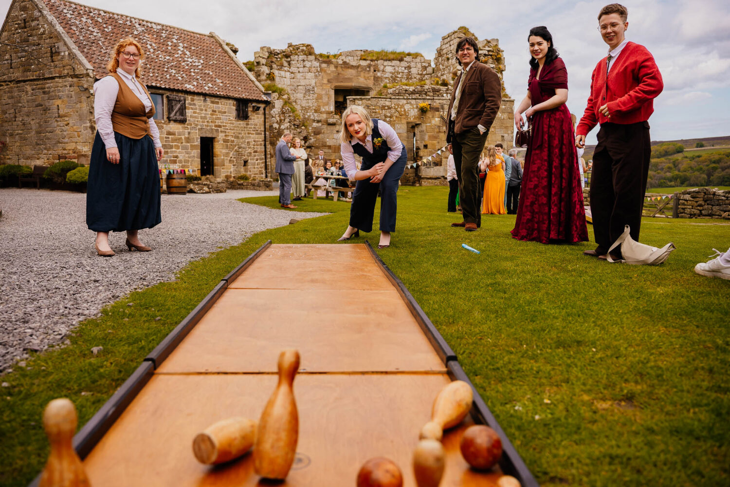 Group gathered watching as someone bowls skittles