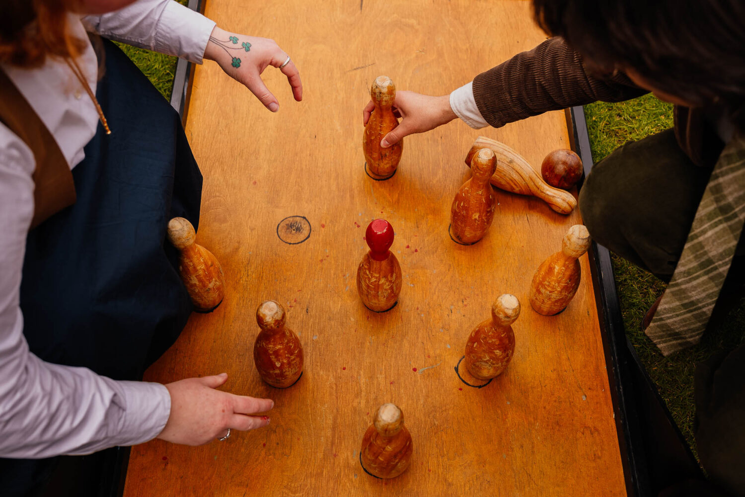 Two people grabbing and resetting bowling pins