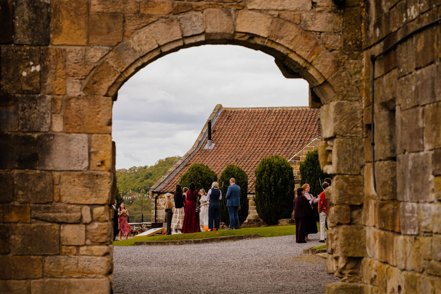People on the lawn at Danby Castle photographed through an archway