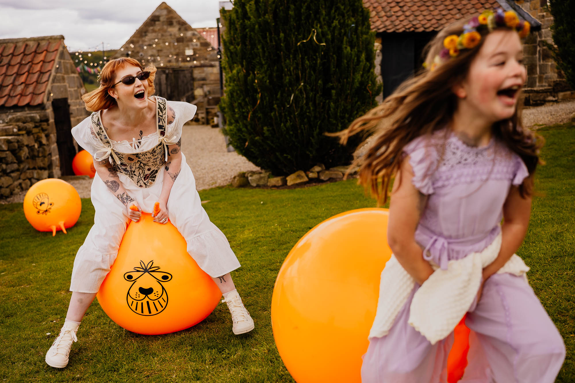 Bride and flower girl on orange space hoppers laughing