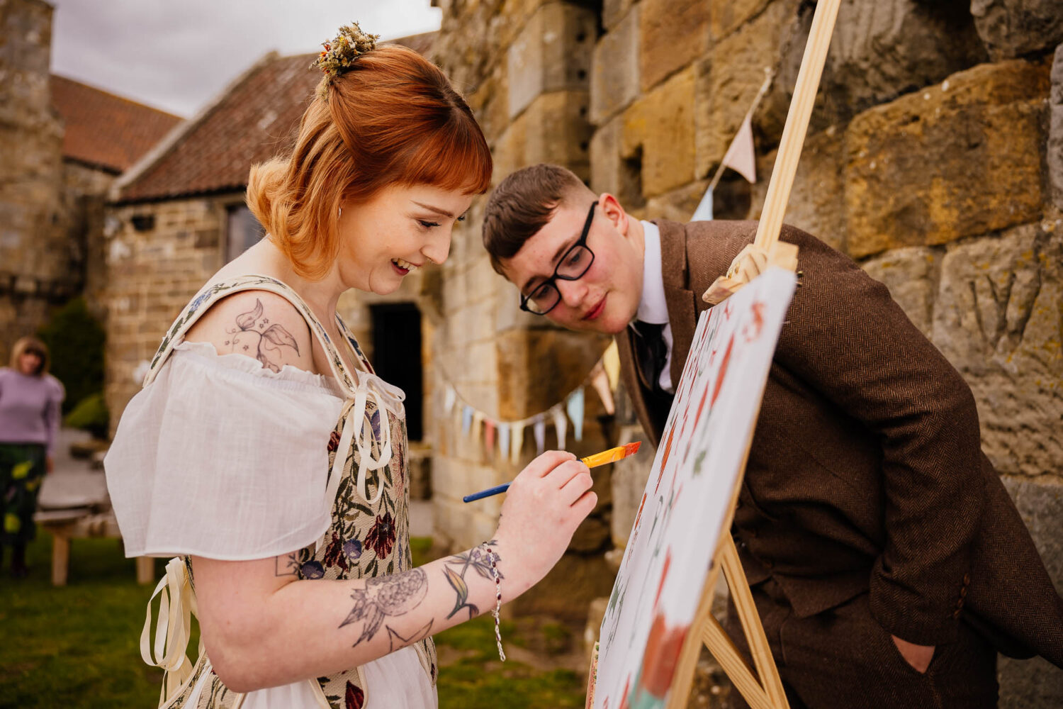 Bride adding paint to canvas whilst guest watches