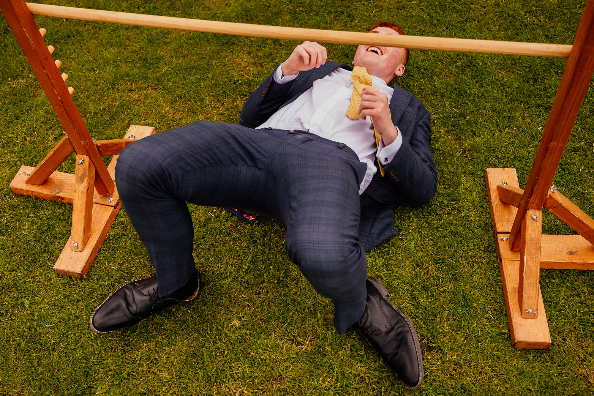 Man lying on grass under limbo bar
