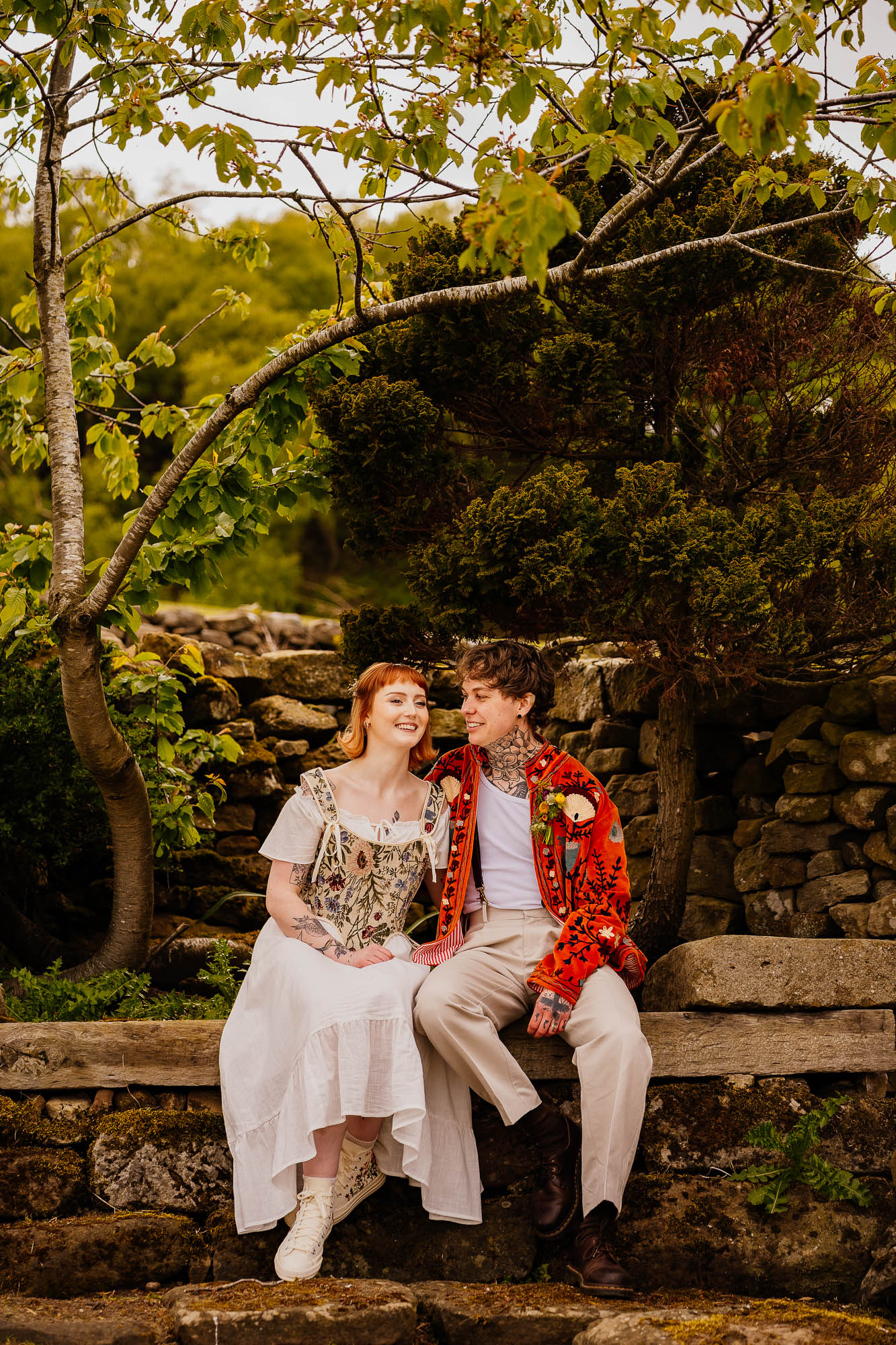 Couple sat on bench smiling with nature behind