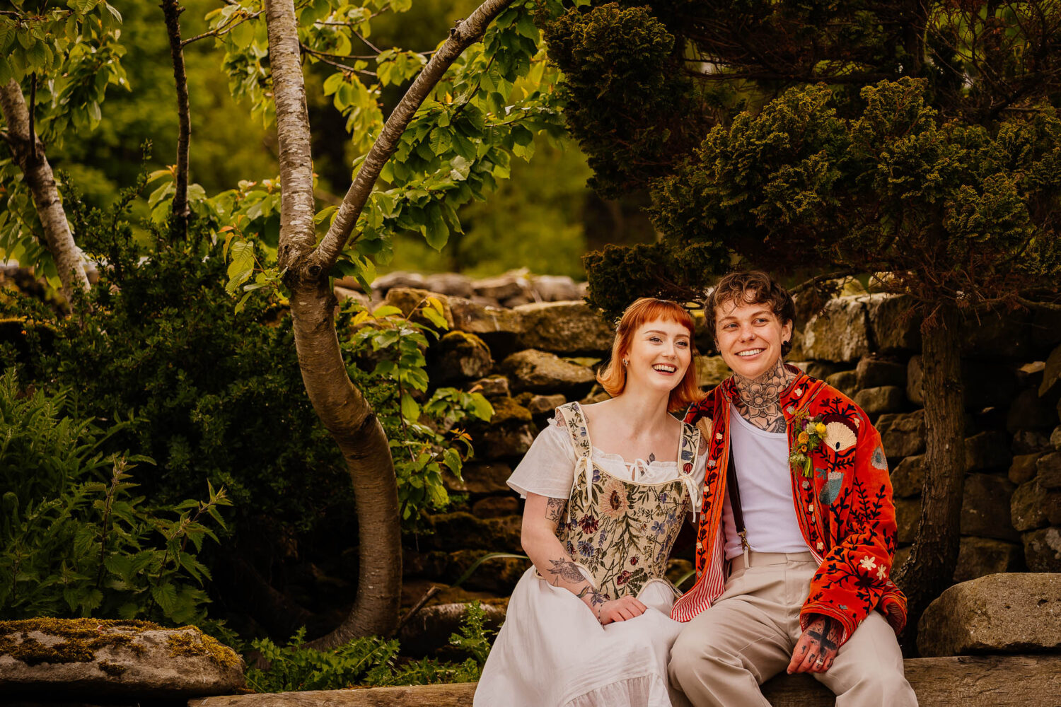 Couple sat together smiling with greenery in the background
