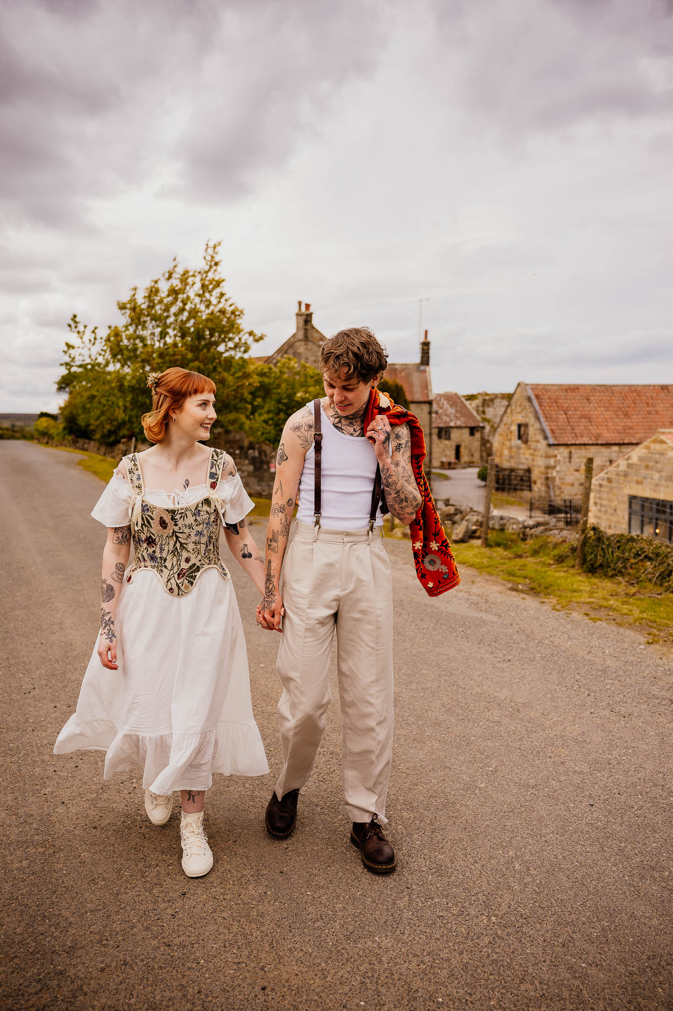 Couple holding hands walking down the road with Danby Castle behind