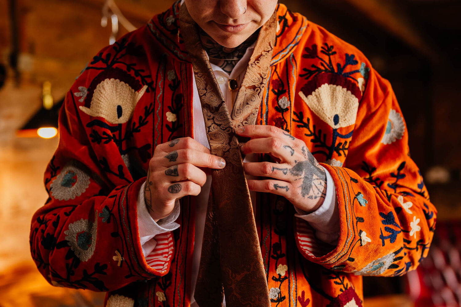 Man tying tie over embroidered jacket