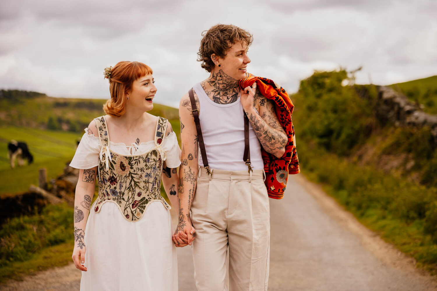 Couple holding hands and walking whilst looking off and smiling