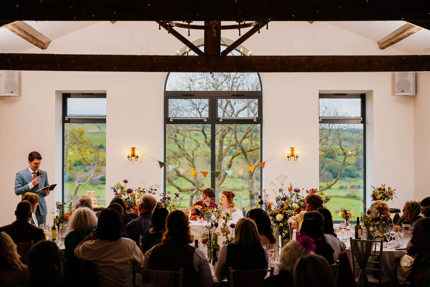 Couple framed under Daleview Barn windows with speaker on the left and audience in front
