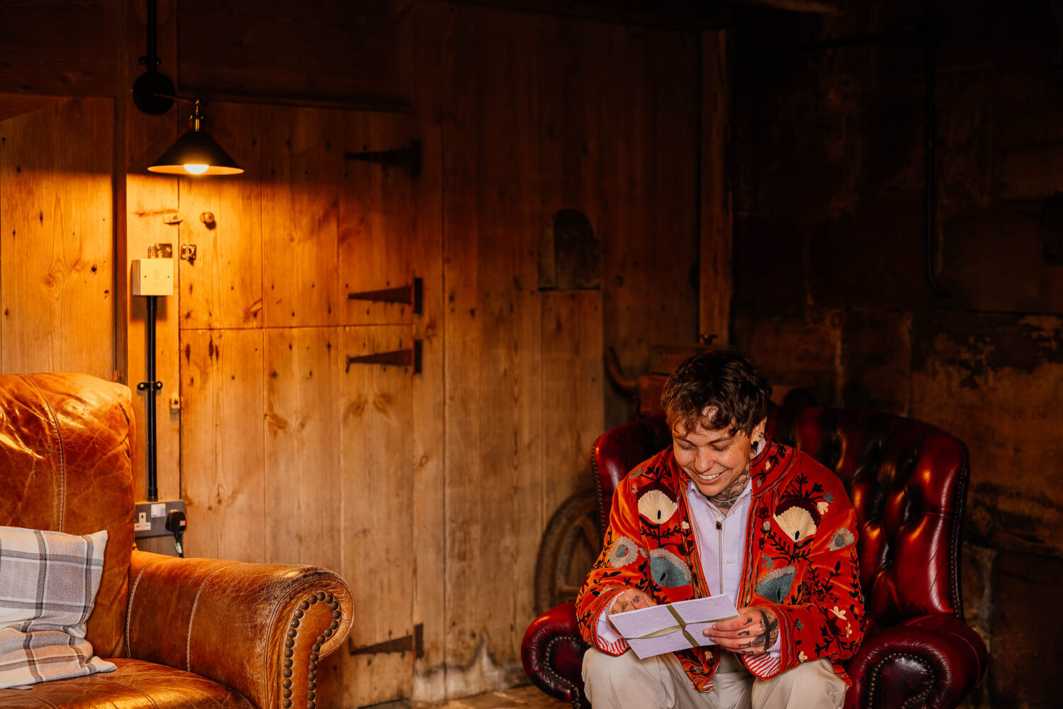 Groom sat in chesterfield chair opening a card